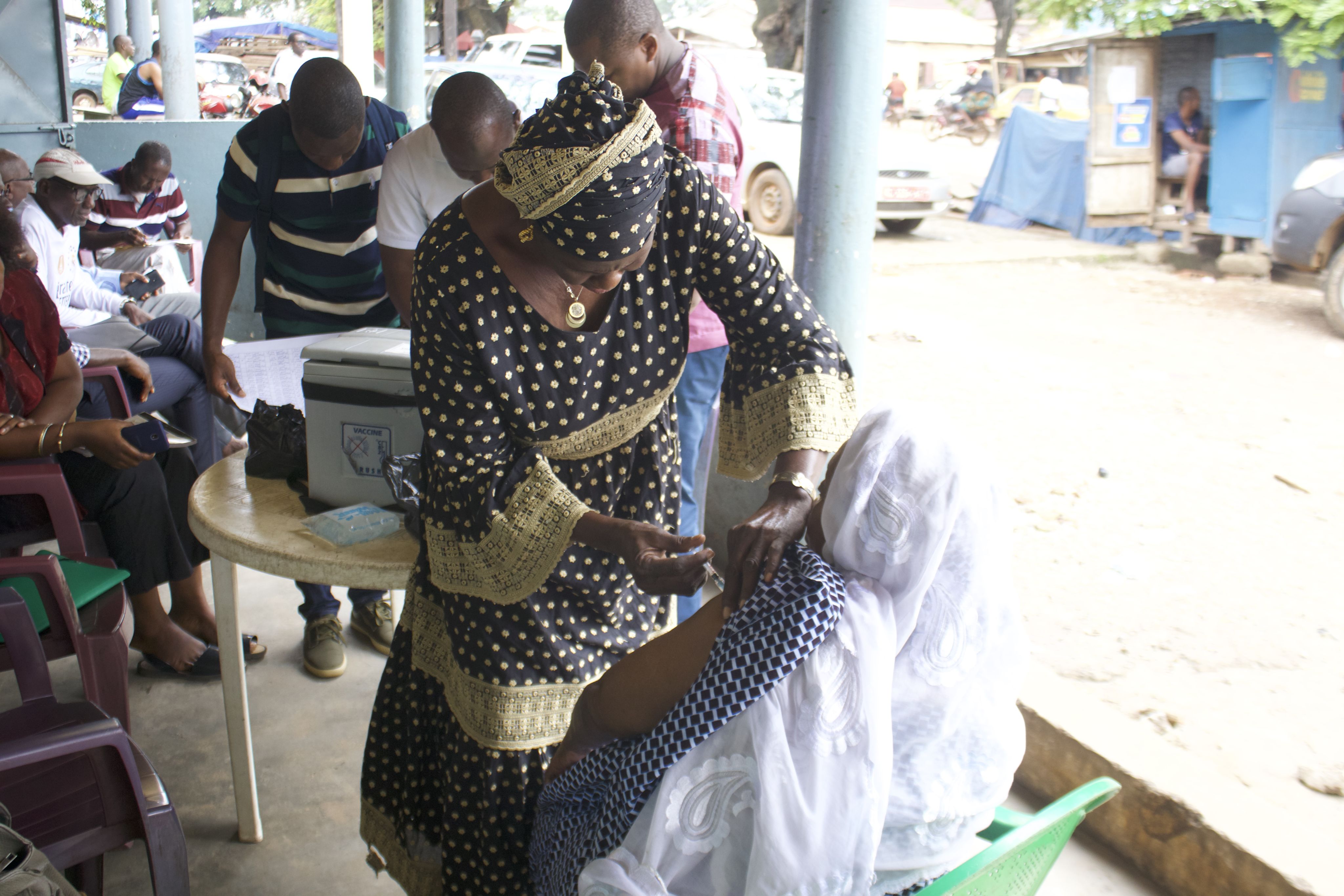 a health worker vaccinates a woman